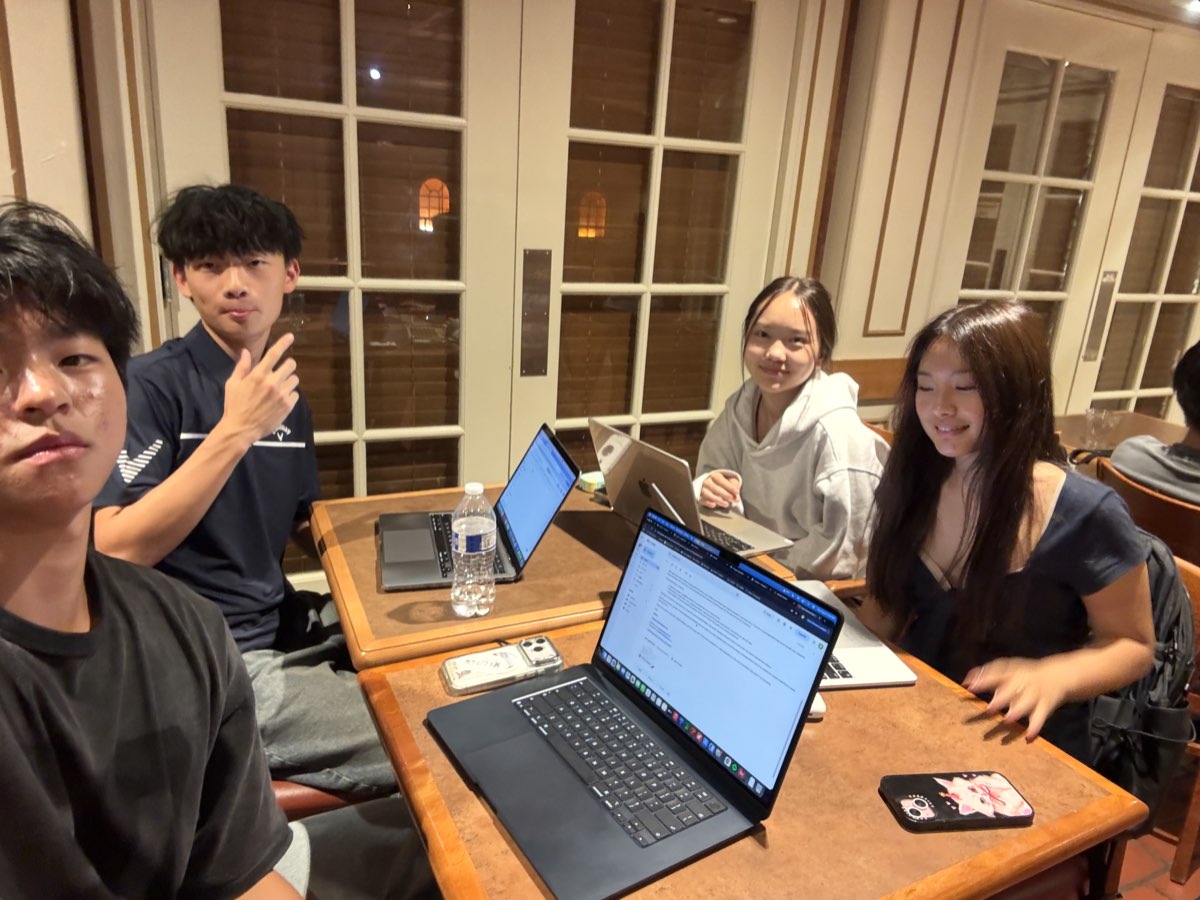 Four UVision team members gathered around a table with laptops, planning the Summer 2026 outreach launch.