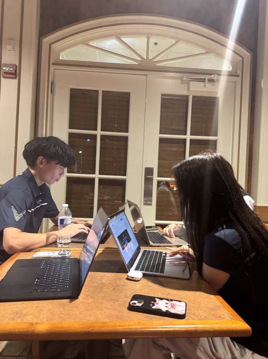 Two UVision team members working on laptops across a table during a planning session.